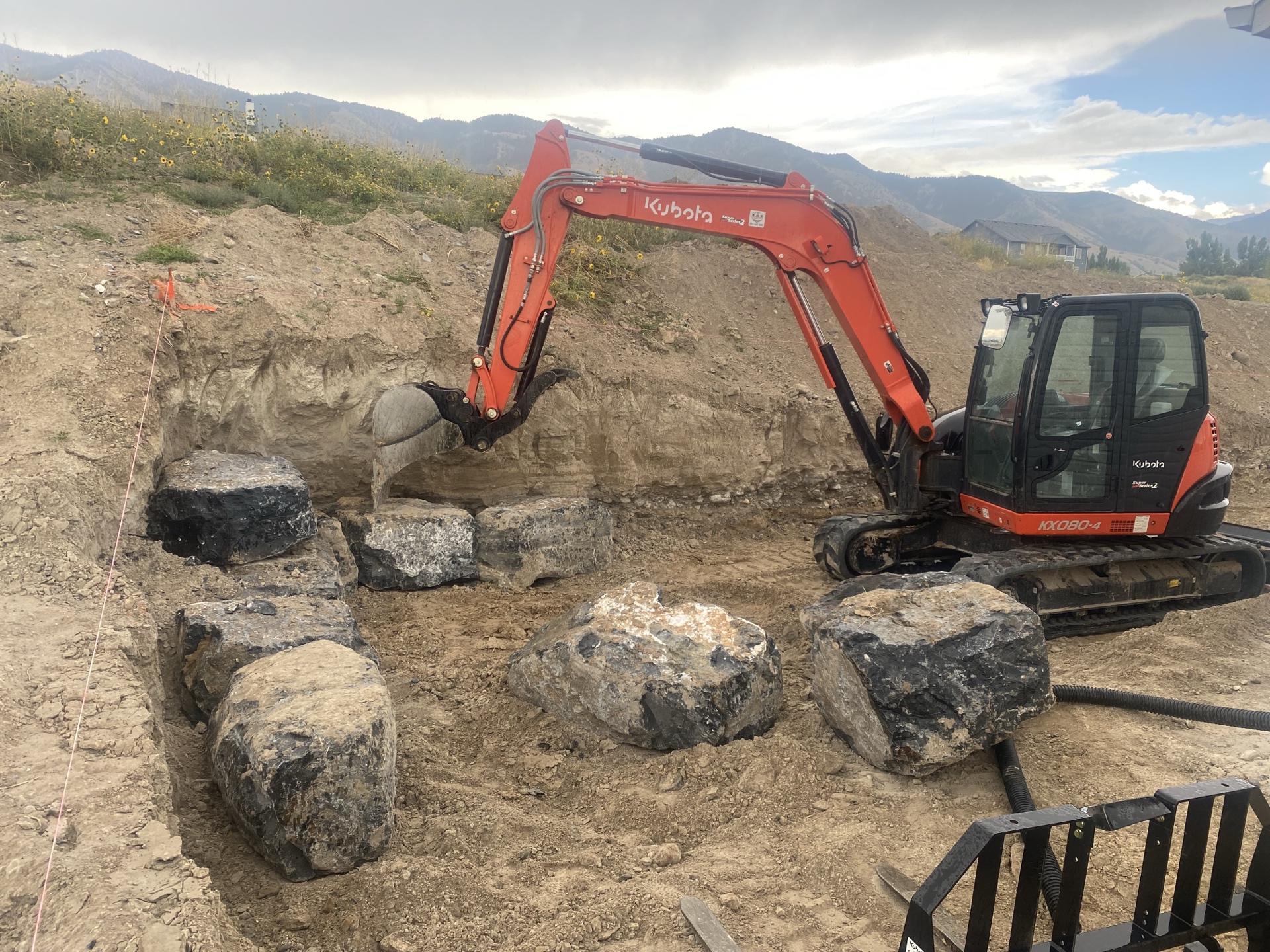 Kubota excavator removing large boulders from site