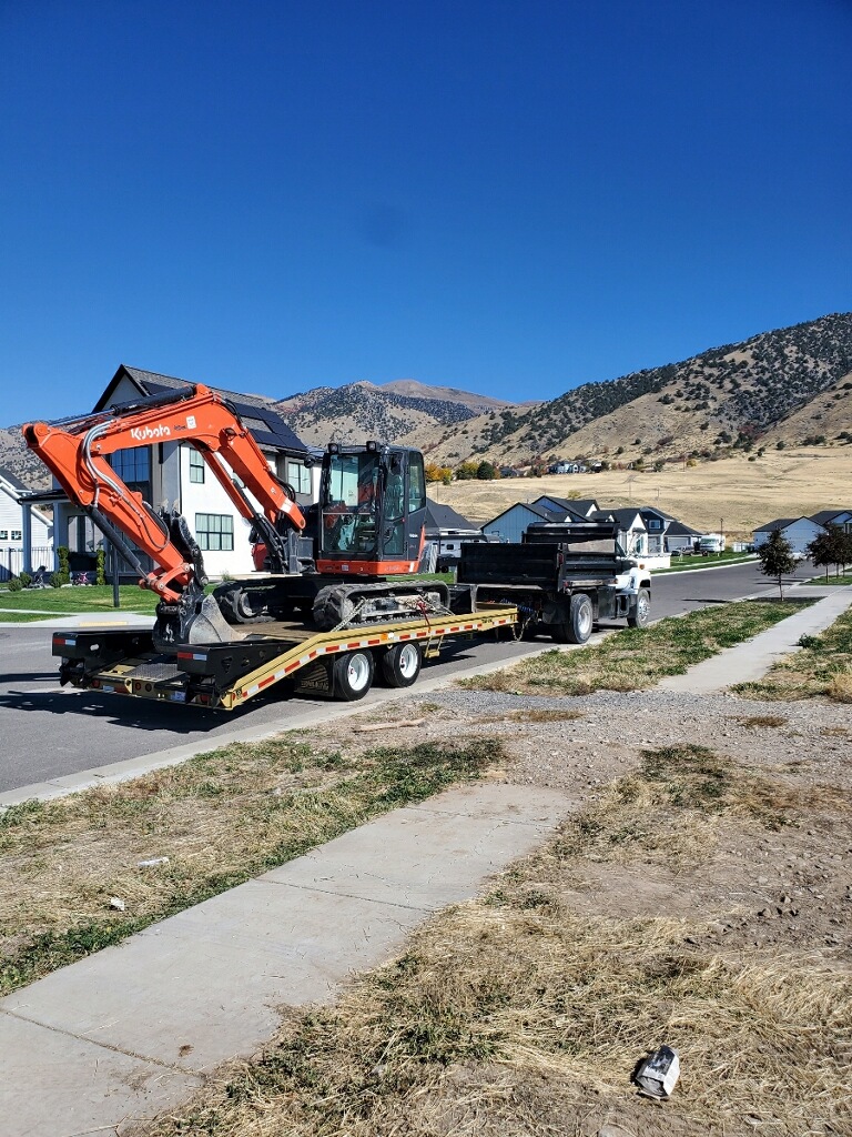 Excavator loaded on flatbed truck with mountain backdrop